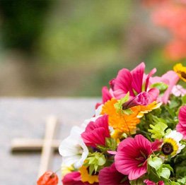 Image of vibrant flowers in front of a casket.